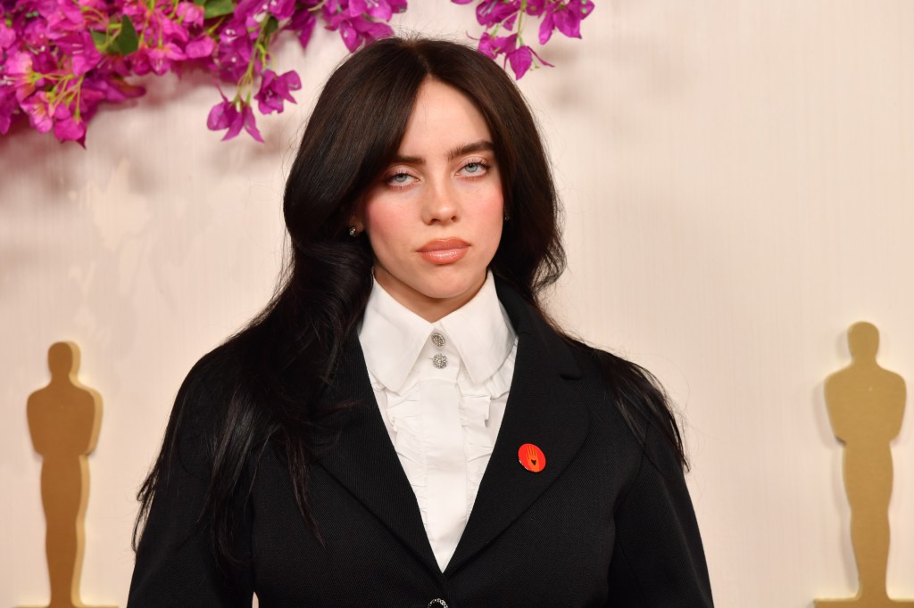 Billie Eilish at the oscars red carpet in a black blazer and white blouse