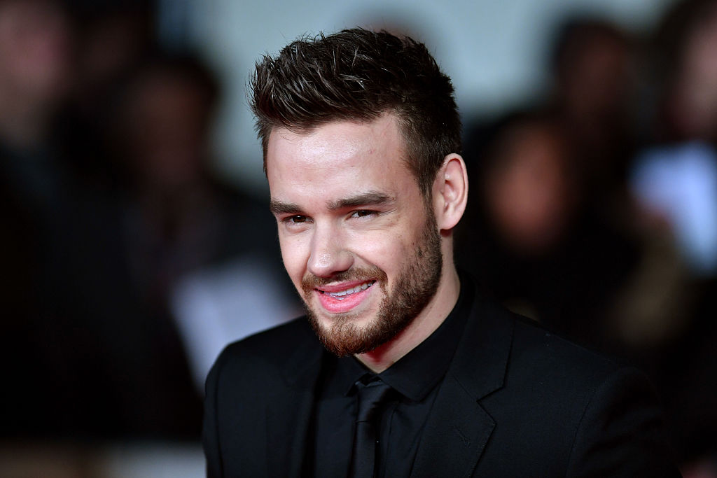 Liam Payne smiles at camera, wearing suit.