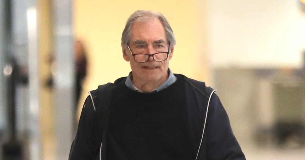 Timothy Dalton in LAX, wearing his glasses on his nose, and a dark jacket