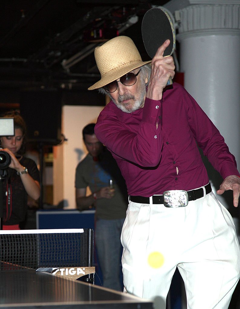 Table Tennis player and author Marty Reisman plays table tennis in red shirt, white pants and hat