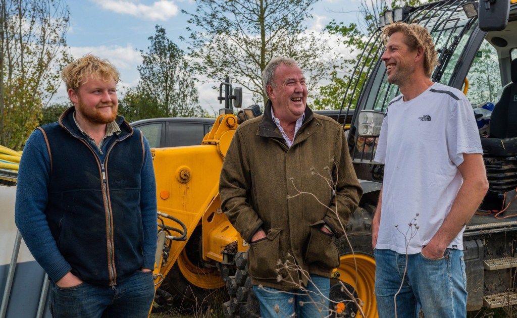 Clarkson's Farm stars Kaleb Cooper and Jeremy Clarkson standing in front of a tractor