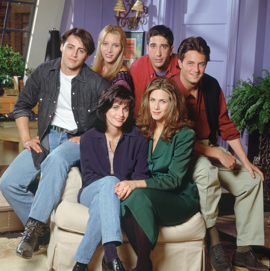 The cast of Friends pose for a photo on a chair in the 1990s