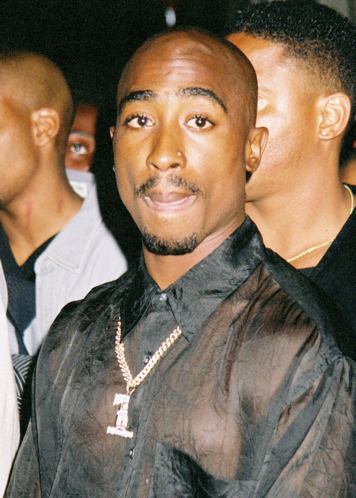 Tupac in black sheer shirt with diamond '1' necklace around his neck