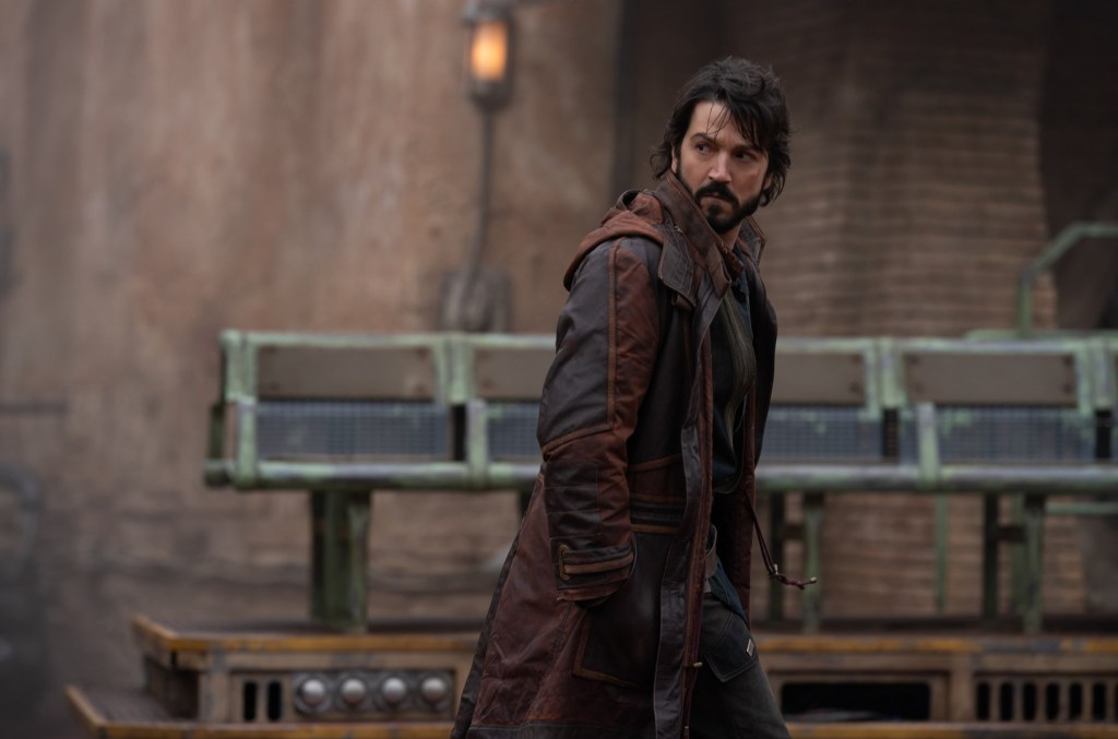 Diego Luna as Cassian Andor in Andor, wearing a long dark coat and looking over his shoulder