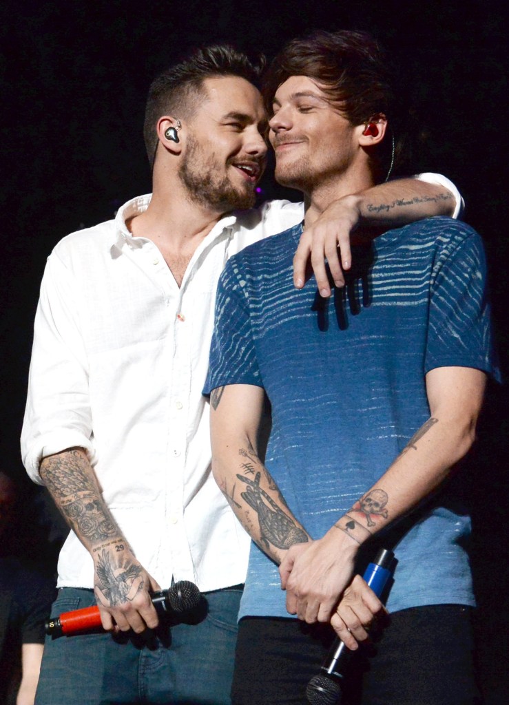 Liam Payne smiles on stage looking at Louis Tomlinson