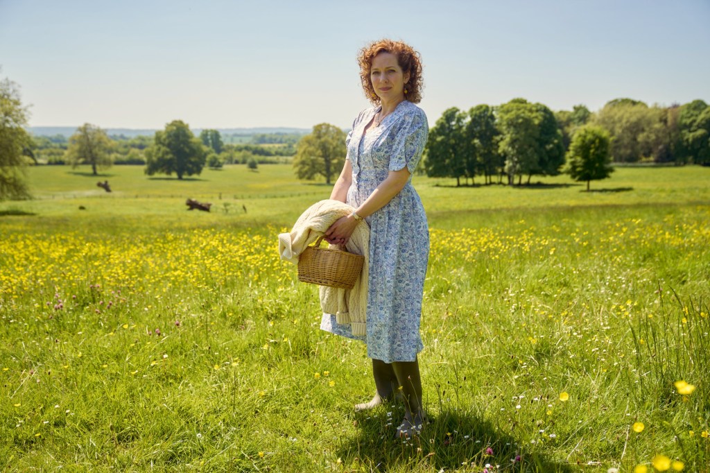 Katherine Parkinson as Lizzie wearing a floral dress and stood in a field in Rivals 