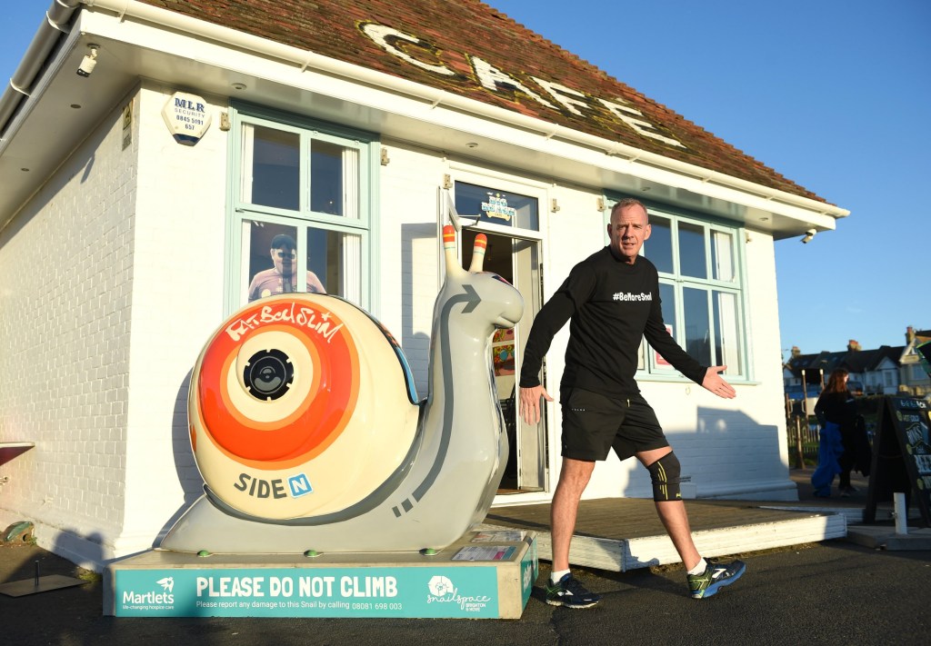 Norman Cook aka Fatboy Slim in front of a cafe and a large snail statue