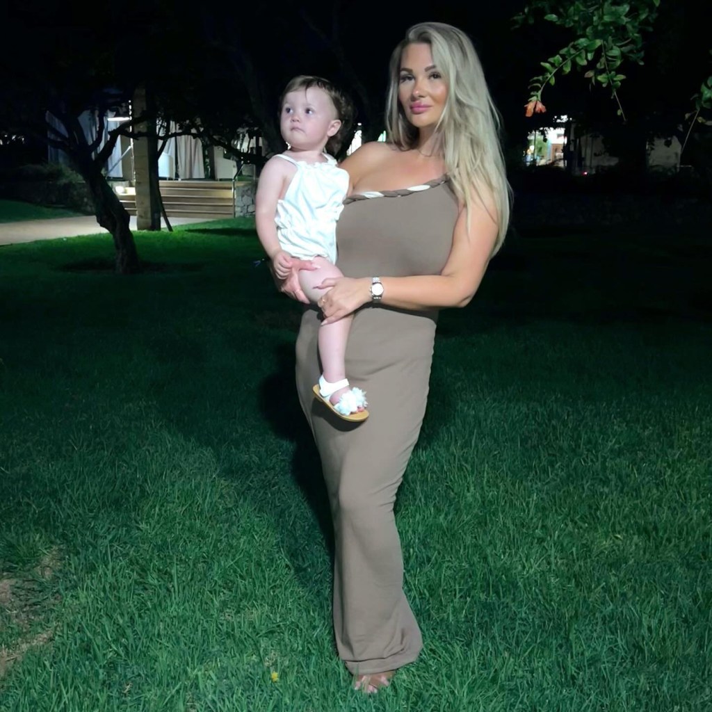 Shaughna Phillips holds one year old daughter as she stands on grass for photo