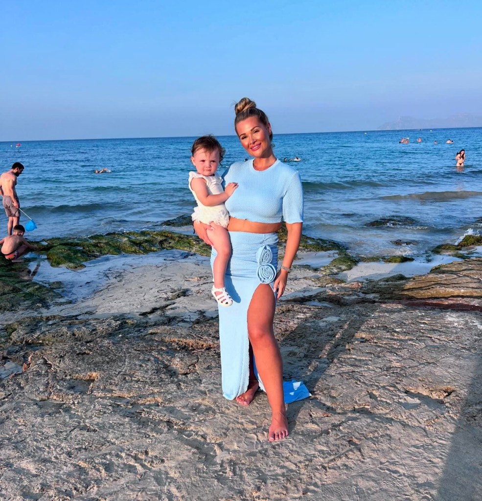 Shaughna Phillips poses with her one year ol daughter on rocks by ocean